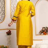 Back view of the mustard yellow Vichitra silk kurta set showing the plain kurta back, three-quarter sleeves with contrast detailing, straight pants, and coordinated festive silhouette.