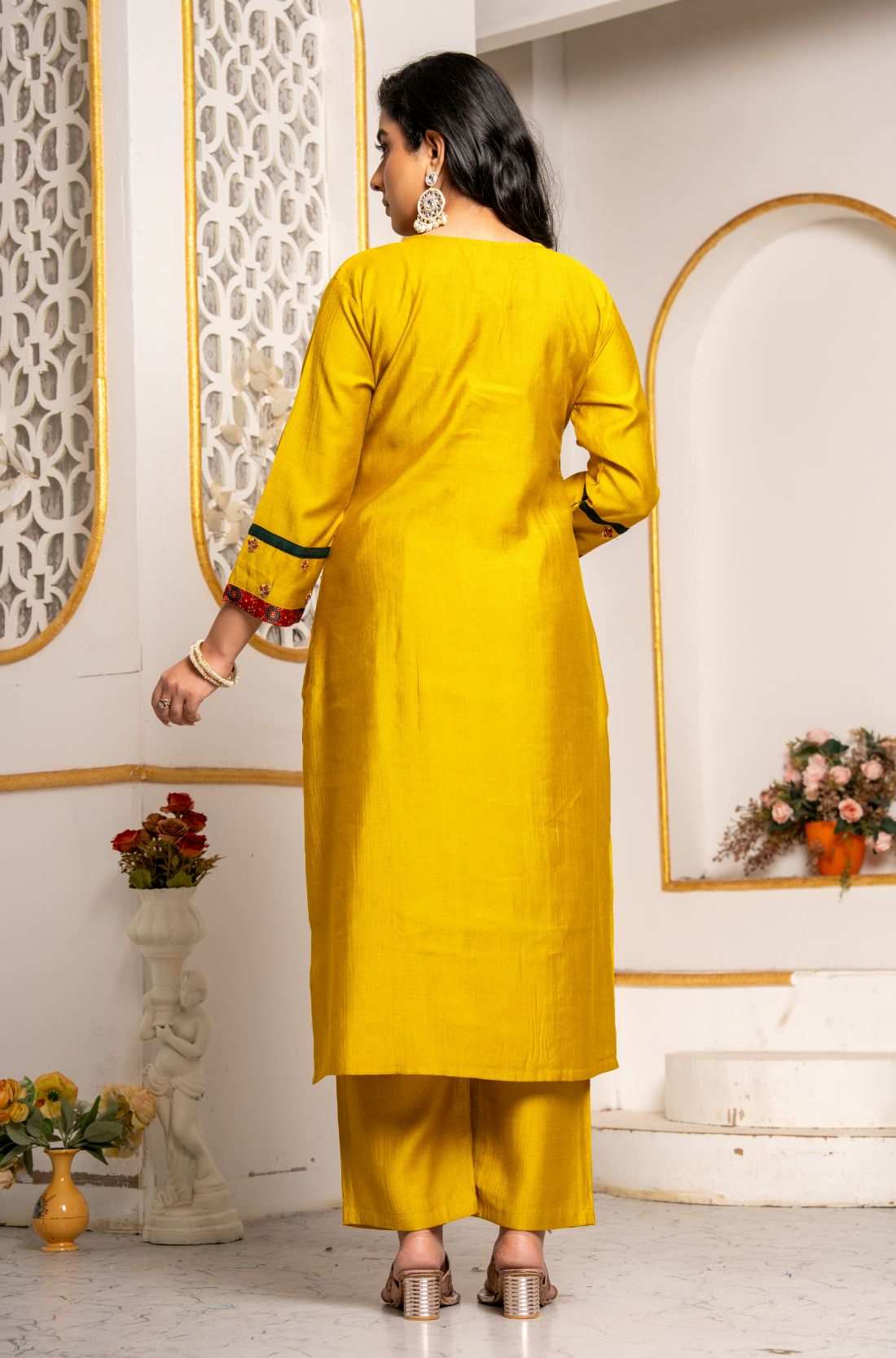 Back view of the mustard yellow Vichitra silk kurta set showing the plain kurta back, three-quarter sleeves with contrast detailing, straight pants, and coordinated festive silhouette.
