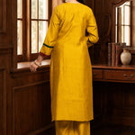 Back view of the mustard yellow Vichitra silk kurta set showing the plain kurta back, three-quarter sleeves with contrast detailing, straight pants, and coordinated festive silhouette.
