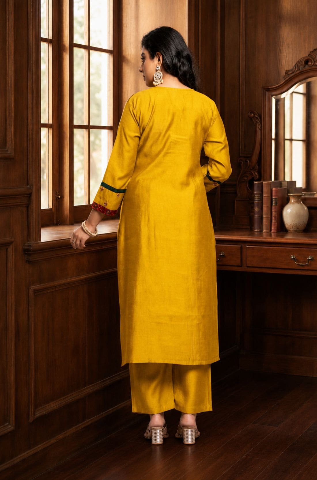 Back view of the mustard yellow Vichitra silk kurta set showing the plain kurta back, three-quarter sleeves with contrast detailing, straight pants, and coordinated festive silhouette.