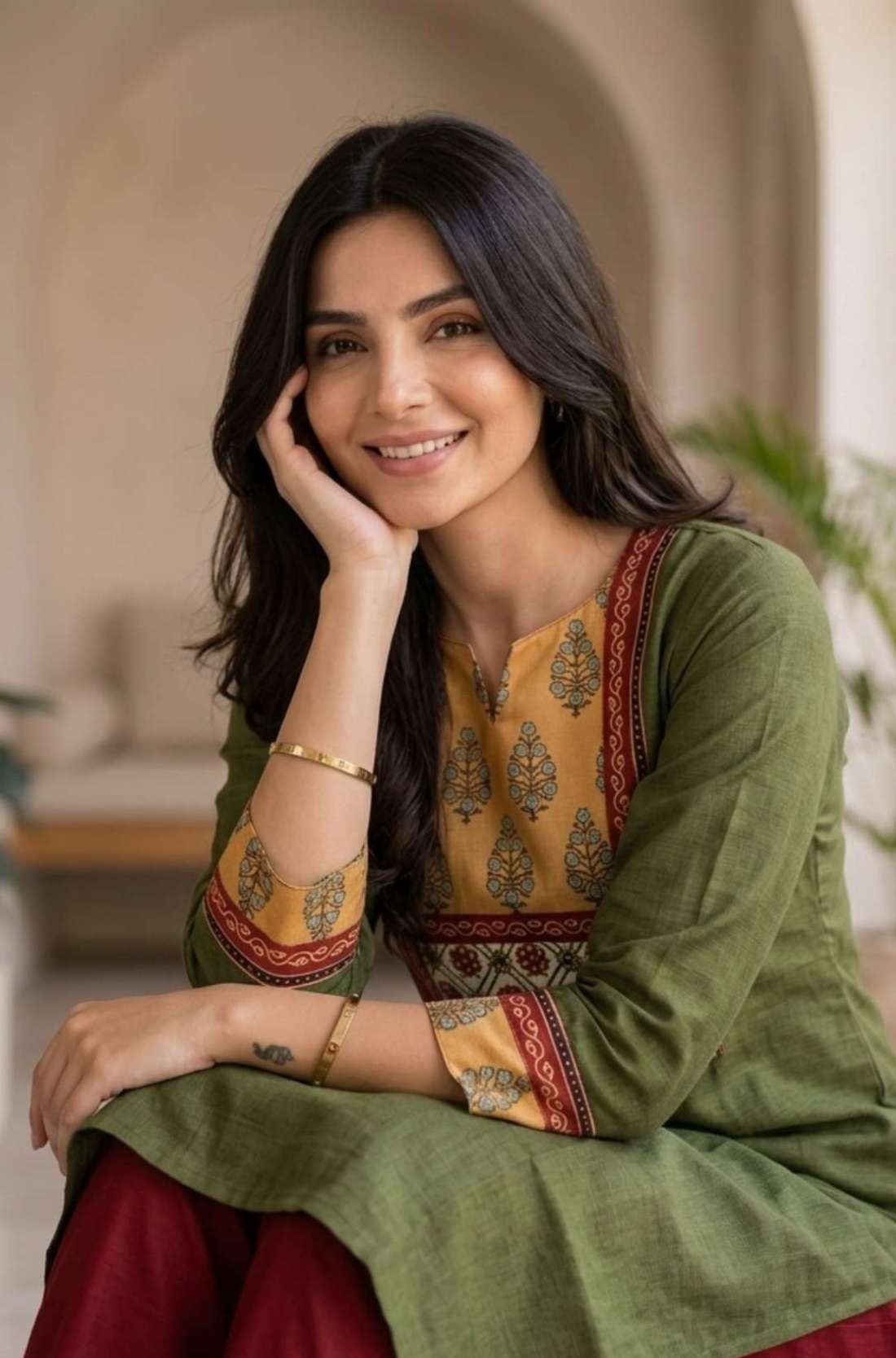 Close-up of the round neckline and contrast mustard, red, and white printed patch yoke with hand block print detailing and embroidered sleeve borders on a dark green cotton kurti.