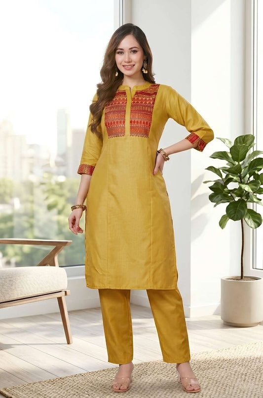 Front view of women's embroidered yoke cotton straight kurta set with pocketed pants in mustard yellow, featuring a printed embroidered yoke, 3/4 sleeves, and straight-fit trousers.