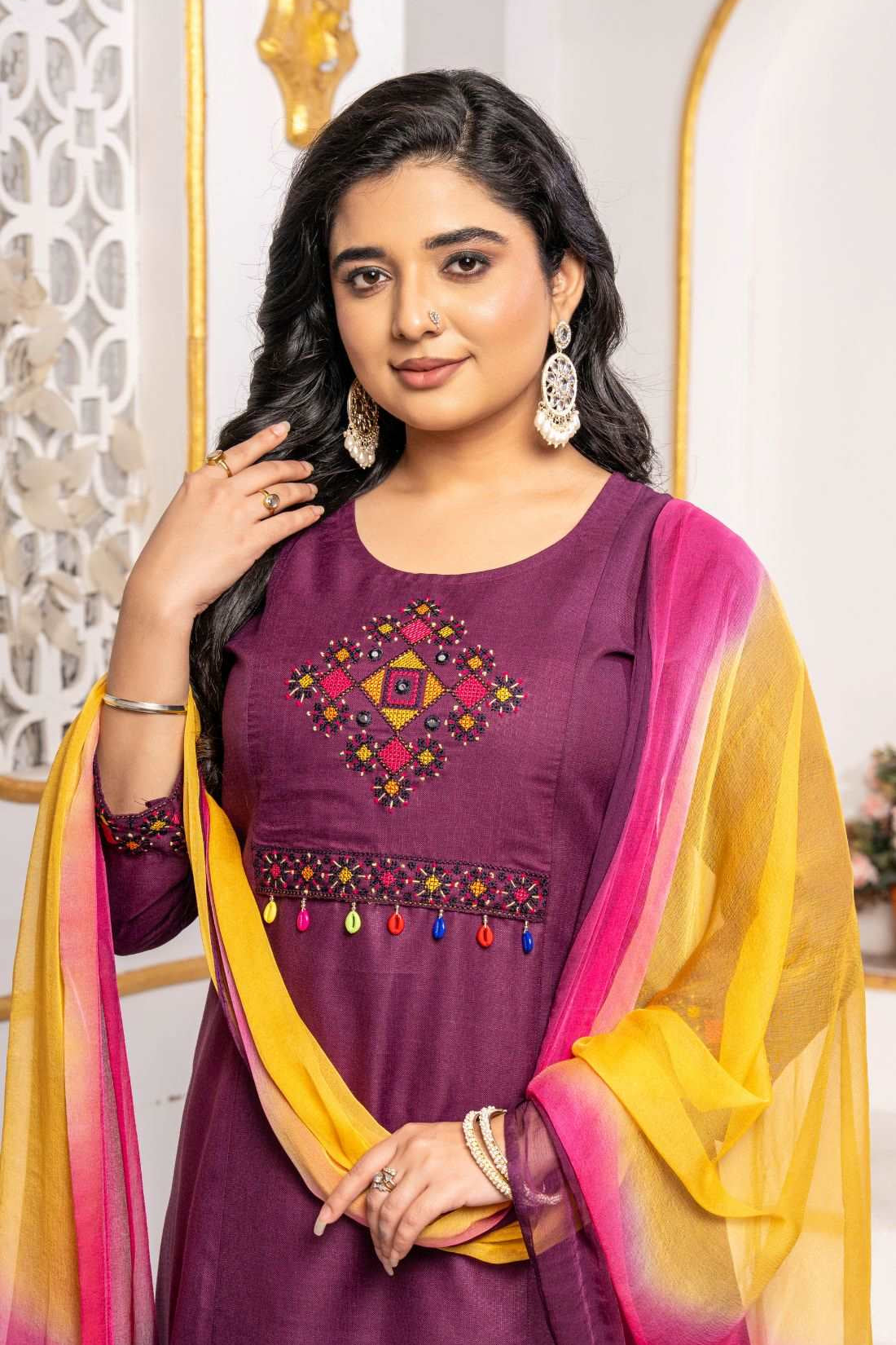 Close-up of a magenta pure cotton kurta featuring a round neckline and intricate multicolour geometric cross-stitch embroidery with mirror detailing, paired with an ombre chiffon dupatta.