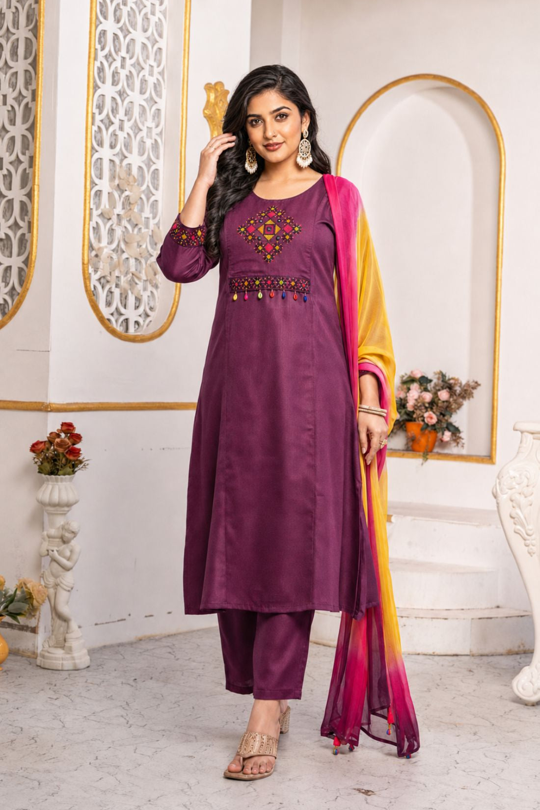 Model wearing a magenta pure cotton kurta pant set featuring multicolour geometric cross-stitch embroidery with mirror detailing, three-quarter sleeves, straight-fit pants and an ombre tie-dye chiffon dupatta.