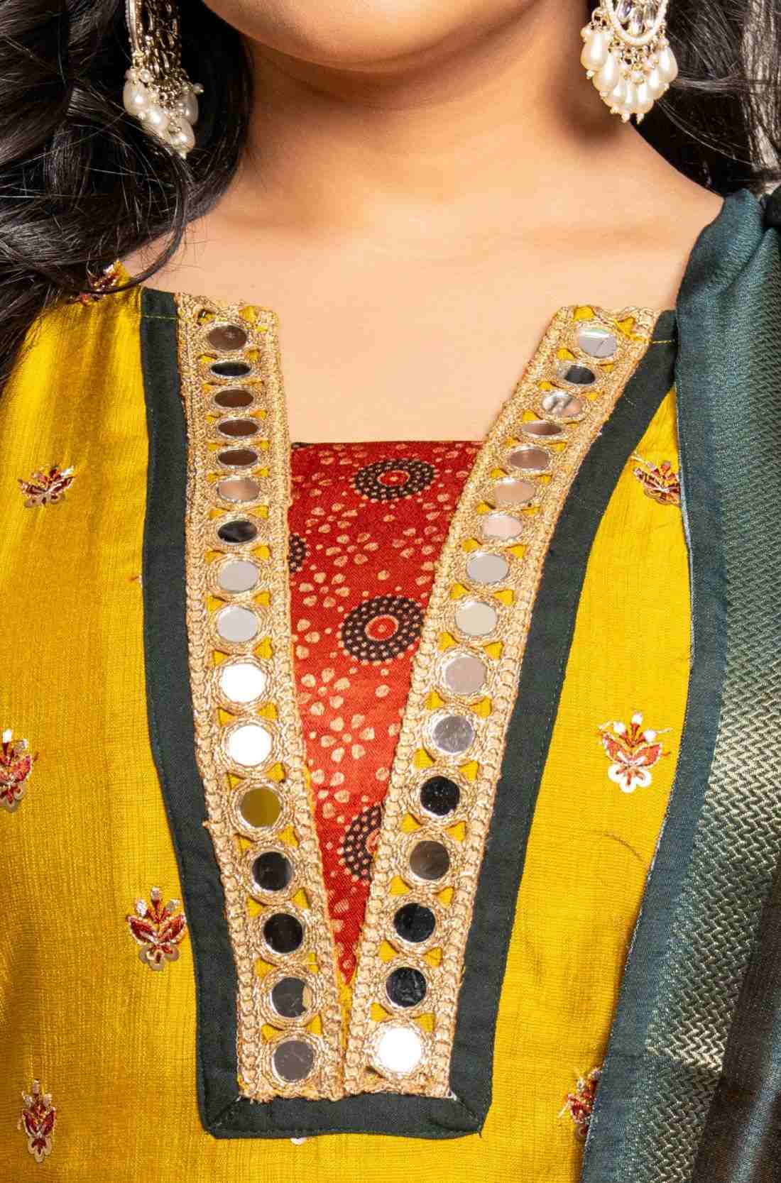 Detailed view of the mustard yellow Vichitra silk kurta neckline showcasing golden mirror work, a contrast Bandhani-print godet, dark green edging, and intricate embroidered floral motifs.