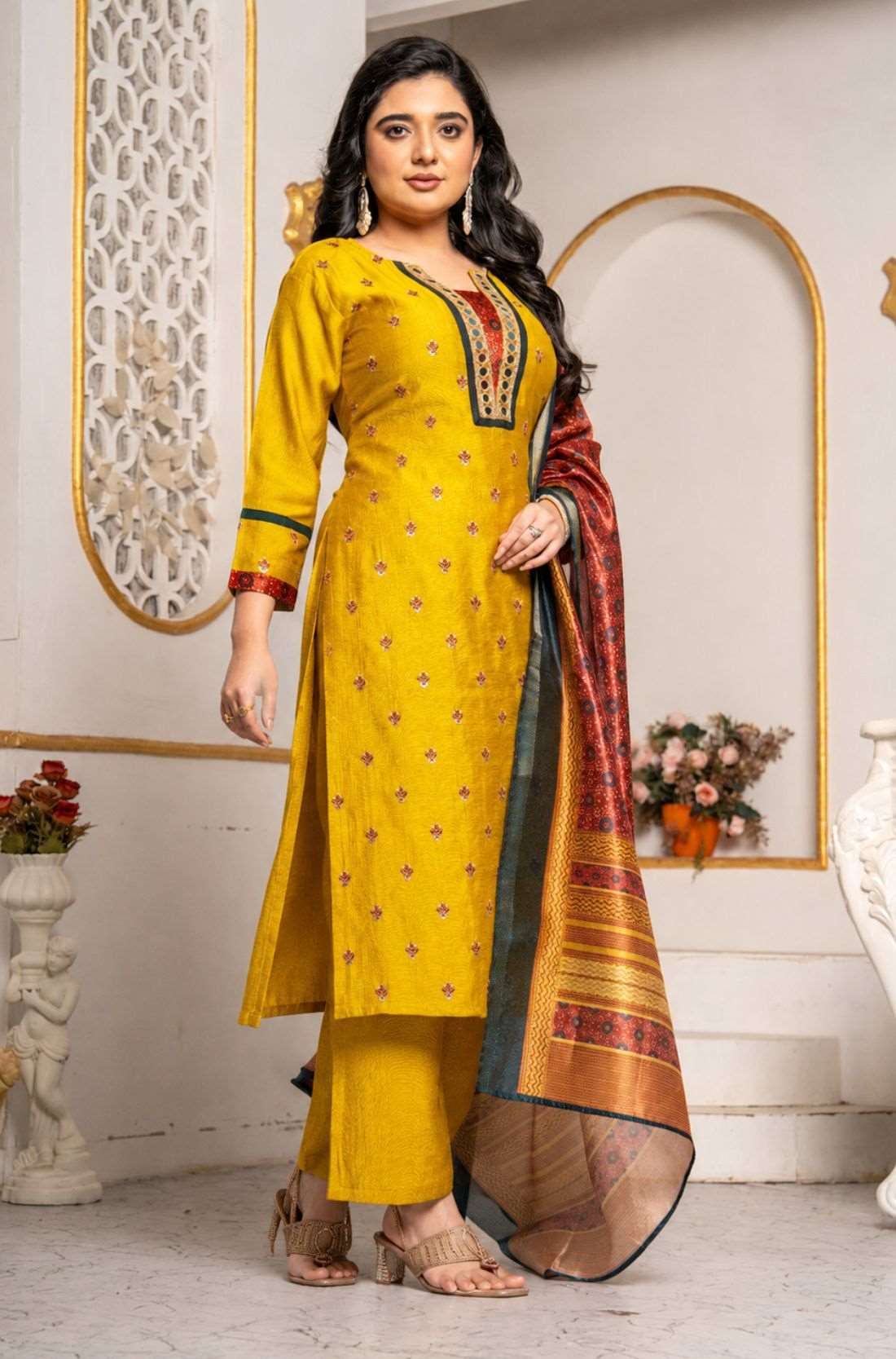 Full-length view of a mustard yellow Vichitra silk kurta set with embroidered kurta, straight-fit pants, three-quarter sleeves, mirror-work neckline, and contrasting printed Chanderi silk dupatta, styled for festive wear.