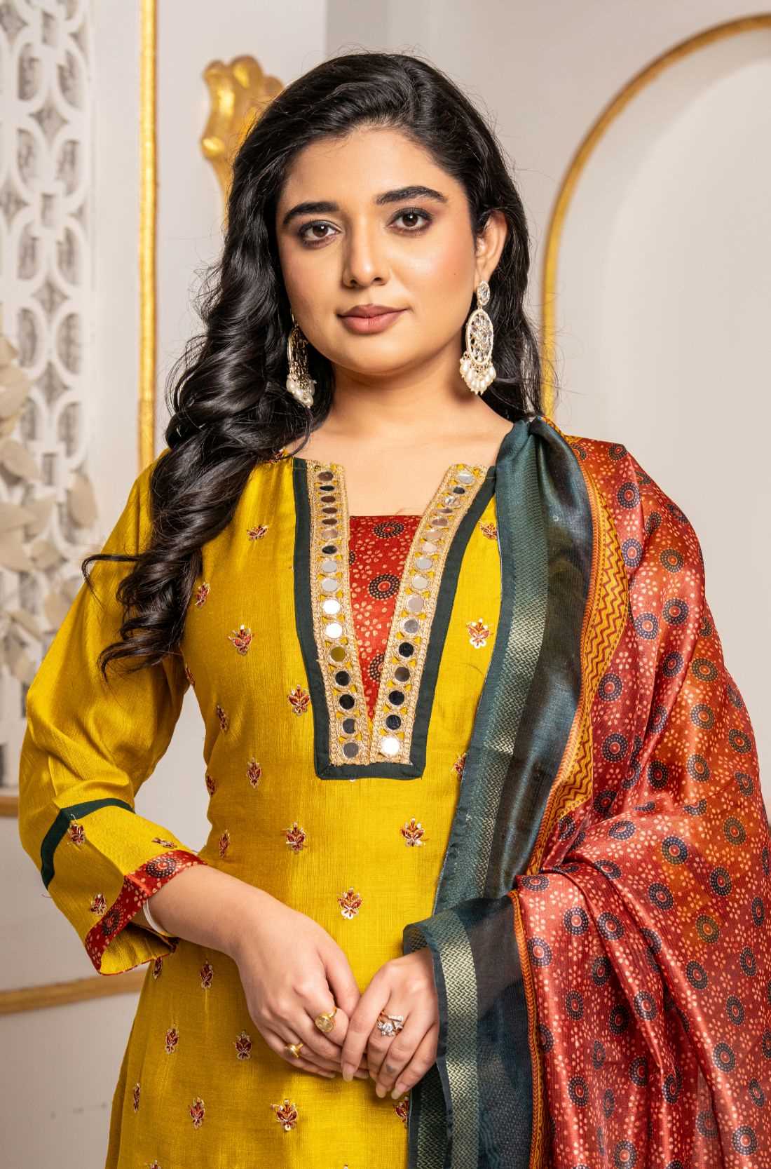 Close-up of a mustard yellow Vichitra silk kurta featuring a V-neckline with golden mirror work, contrast red Bandhani-print insert, delicate sequin and thread embroidery, and a printed Chanderi silk dupatta.
