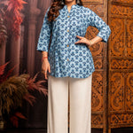Front view of women's powder blue short kurti crafted from pure cotton with hand block floral print, wooden button placket, 3/4 sleeves, mandarin notch neckline, relaxed fit and side slits paired with white palazzo pants.