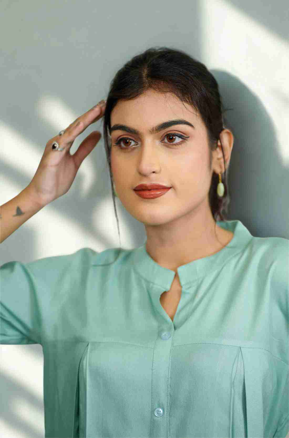 Close-up of the mandarin collar, front button placket, and elegant pleated detailing on a women's sea green rayon formal Top.