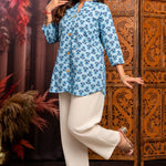 Model wearing powder blue short kurti in pure cotton with hand block floral print, wooden buttons, 3/4 sleeves and white wide-leg pants for a comfortable everyday ethnic look.