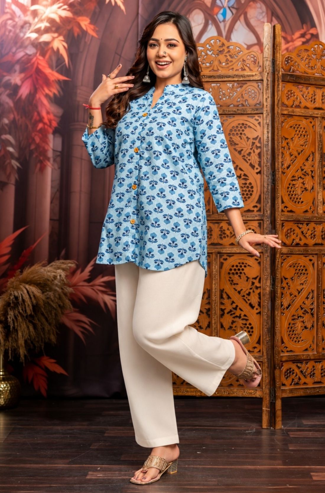 Model wearing powder blue short kurti in pure cotton with hand block floral print, wooden buttons, 3/4 sleeves and white wide-leg pants for a comfortable everyday ethnic look.
