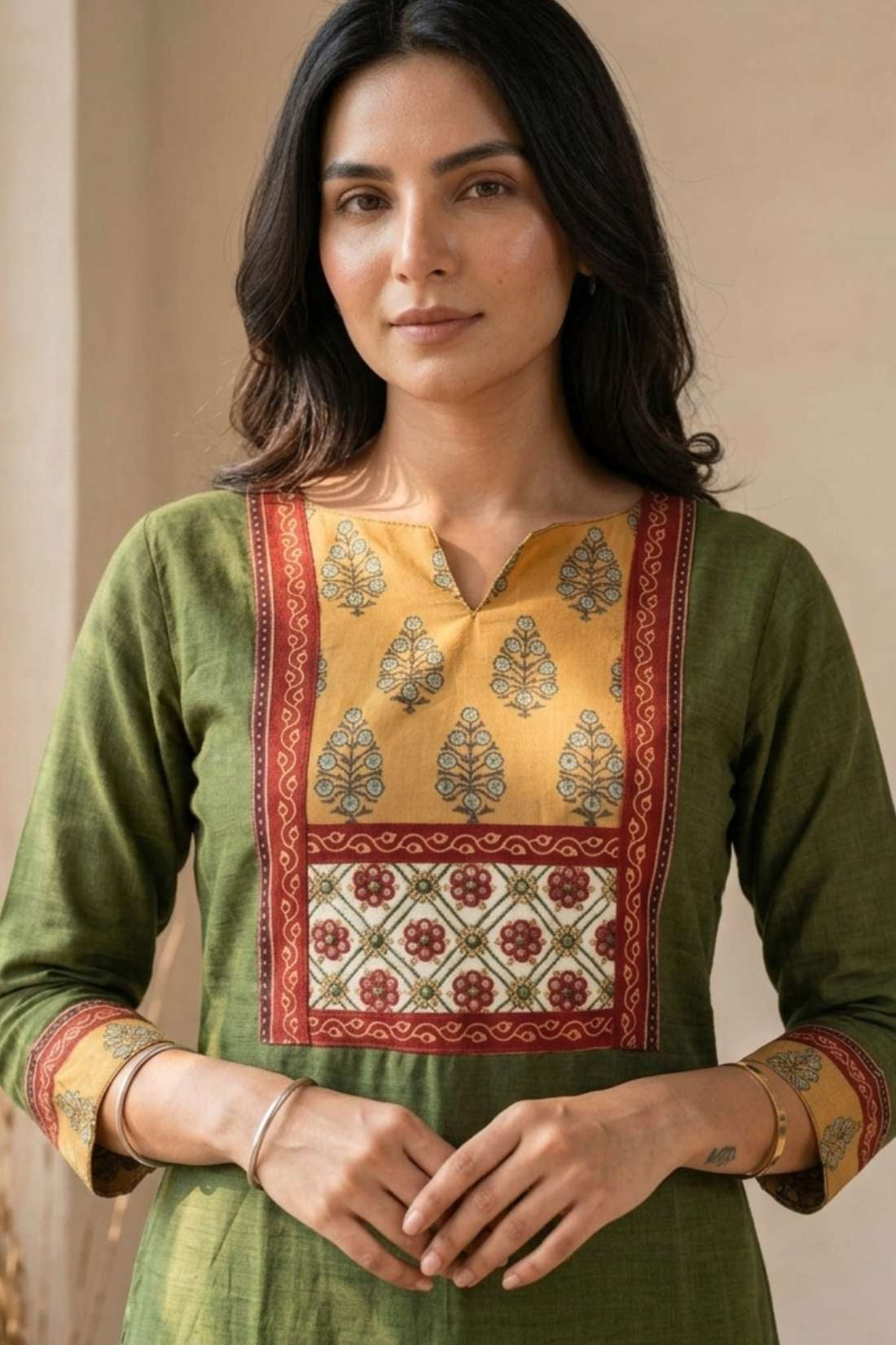 Front view of women's dark green cotton hand block print kurti featuring a round neckline, mustard and red contrast patch yoke, three-quarter sleeves, and a straight calf-length silhouette.
