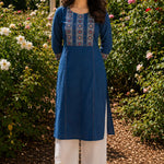 Woman wearing an indigo pure cotton hand block print kurta with mirror work yoke, round neckline and three-quarter sleeves.