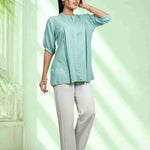 Women's sea green rayon Top with a mandarin collar, front button placket, soft pleats, and half sleeves styled with white trousers for office and everyday wear.