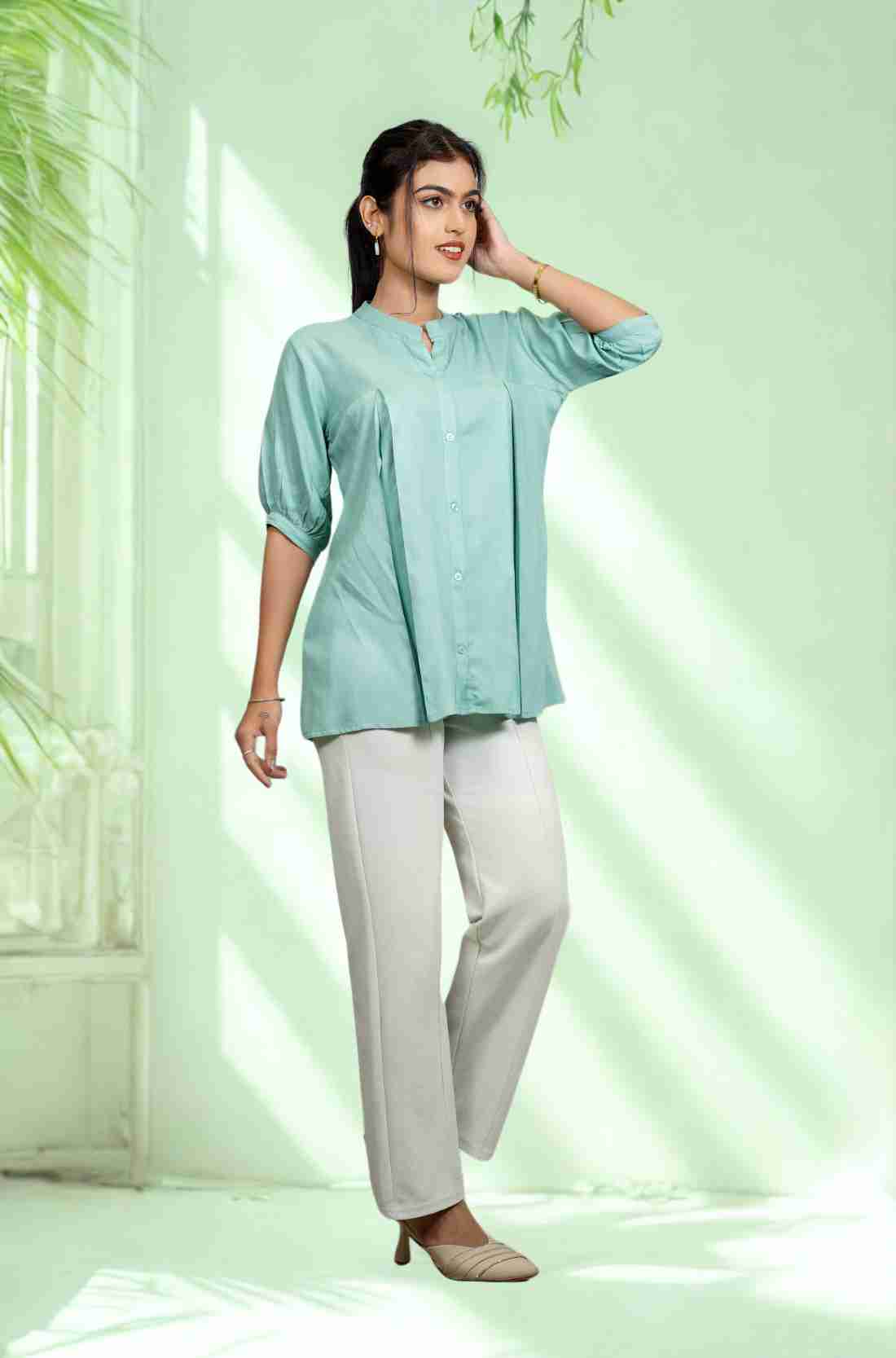Women's sea green rayon Top with a mandarin collar, front button placket, soft pleats, and half sleeves styled with white trousers for office and everyday wear.
