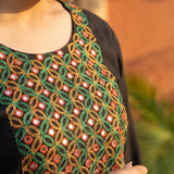 A close-up view of the neckline of a black kurta, highlighting detailed green, red, and gold mirror-work embroidery.