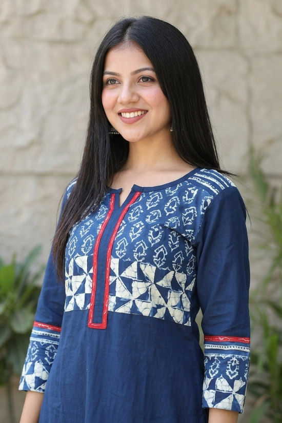 Close-up of a blue kurti with a V-slit neckline, red borders, and white geometric block prints on the yoke.