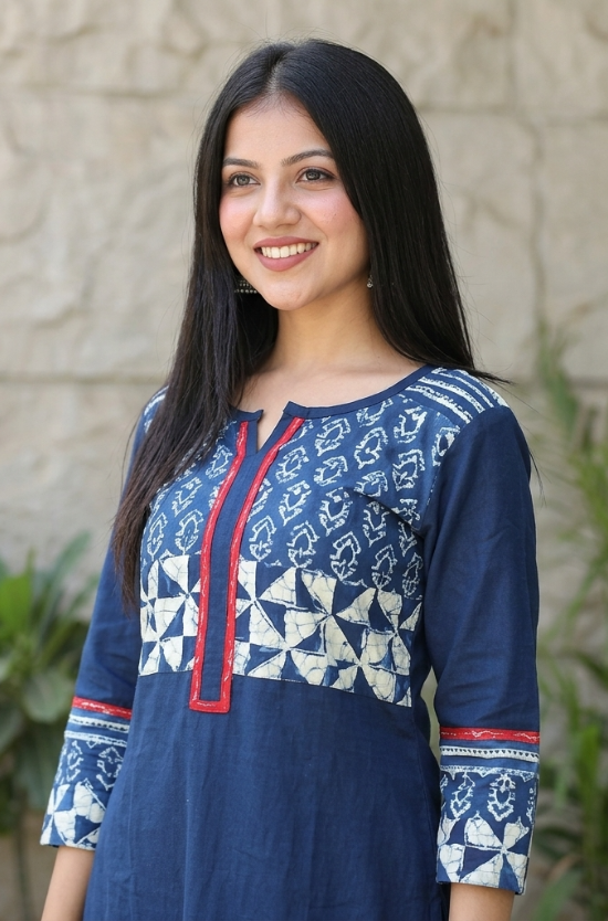 Close-up of a blue kurti with a V-slit neckline, red borders, and white geometric block prints on the yoke.