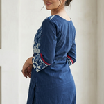 Back view of a woman looking over her shoulder, showcasing the side fit and sleeve prints of a dark blue cotton kurti.