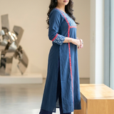 Side profile of a woman showcasing the side slits and red piping design on a beautiful blue long kurti.
