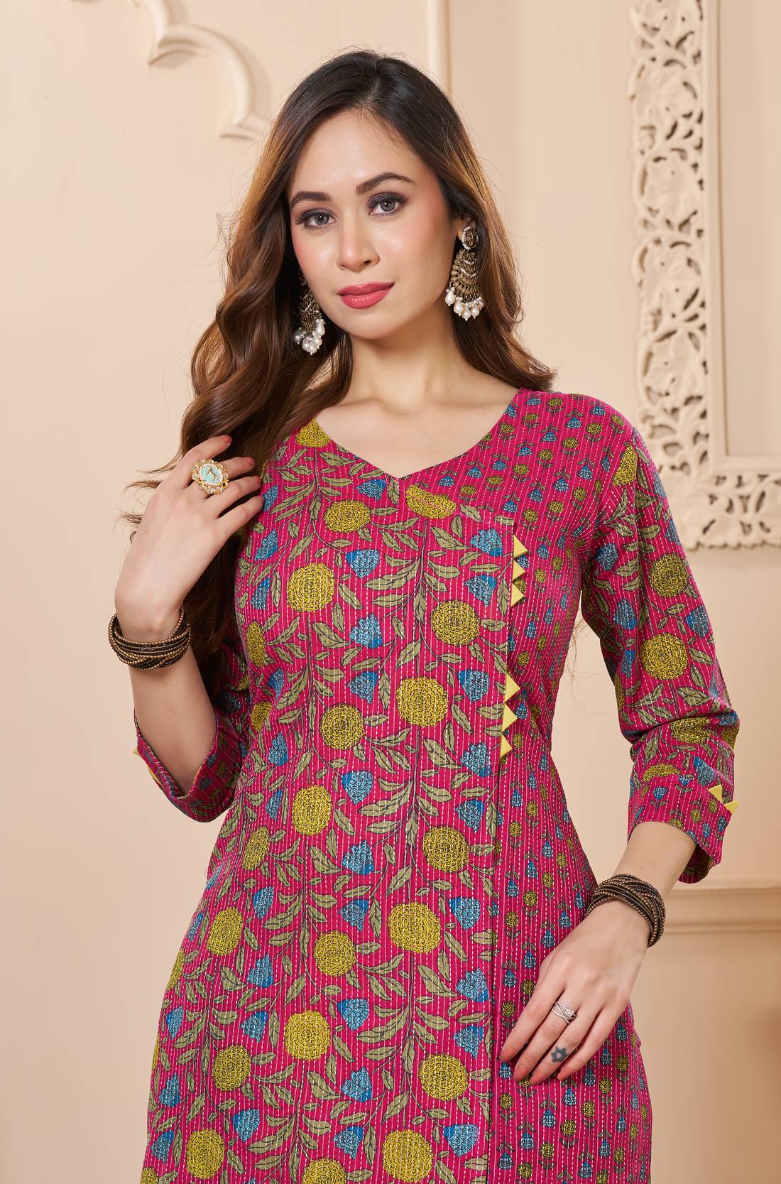 Close up view of the elegant V neckline design showcasing white lace inserts and border trims on a bright pink cotton floral print kurta