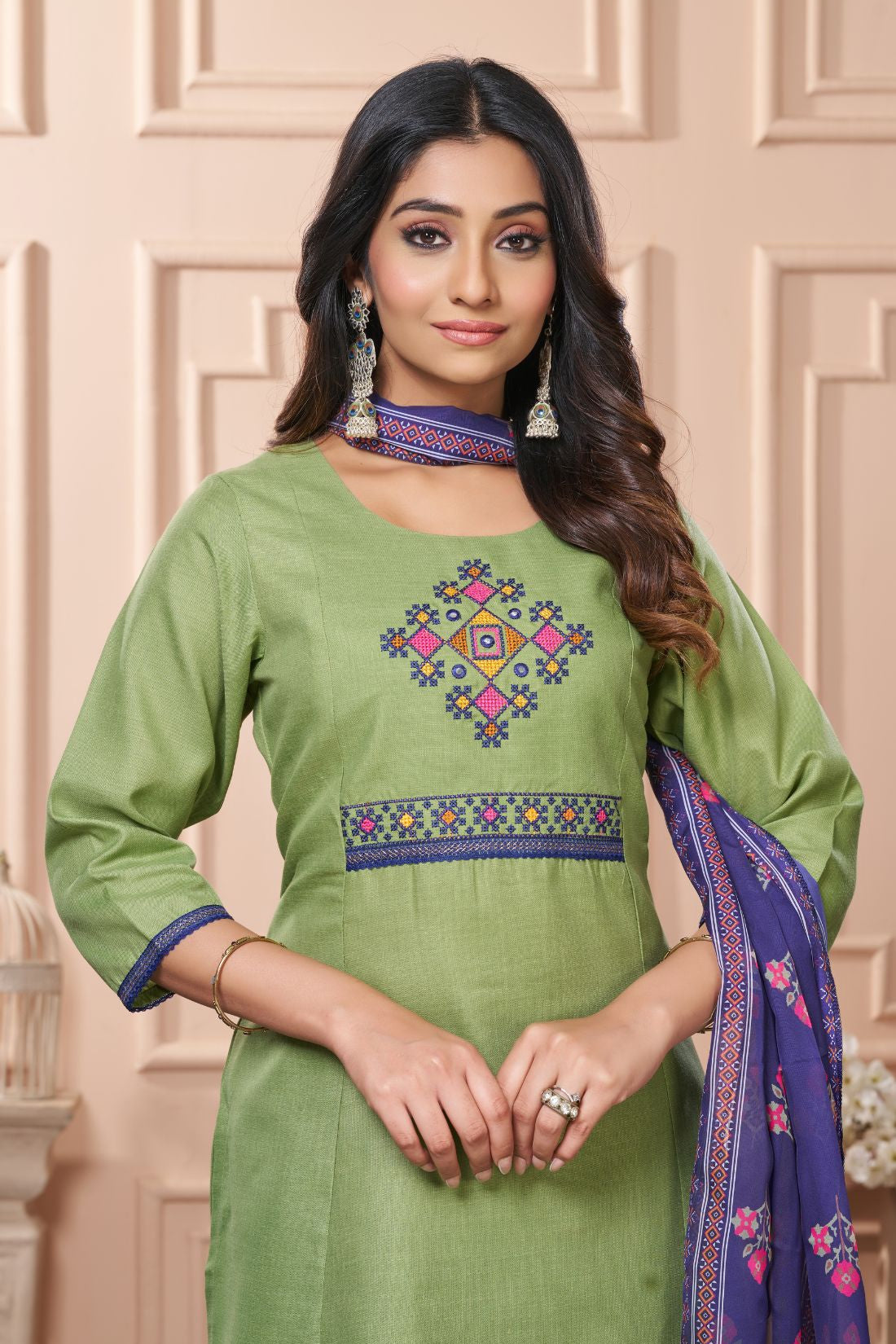 Detailed close up macro shot of the traditional multicolor floral cross stitch embroidery patterns surrounding the split crew neckline of a light green cotton kurta