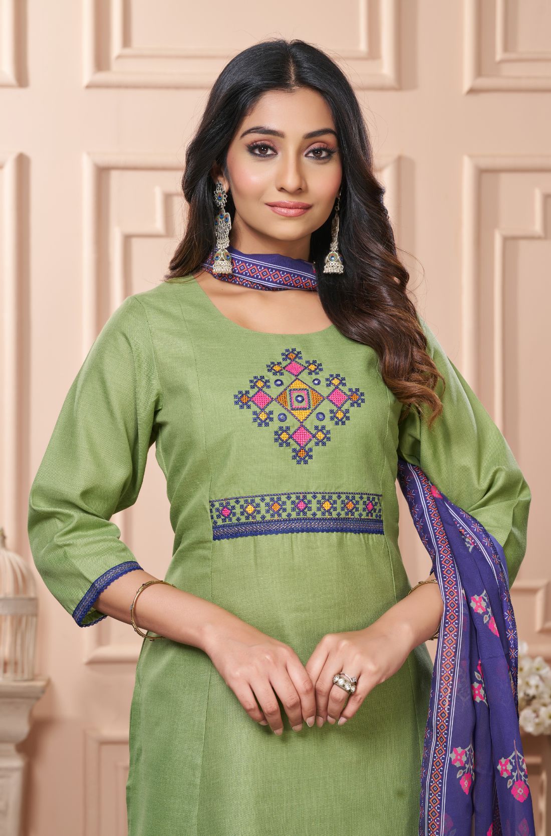 Detailed close up macro shot of the traditional multicolor floral cross stitch embroidery patterns surrounding the split crew neckline of a light green cotton kurta