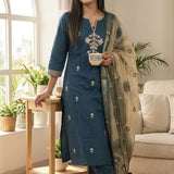 Angled view of a woman posing in a luxurious dark blue silk kurta set displaying the intricate pattern of the orange dupatta