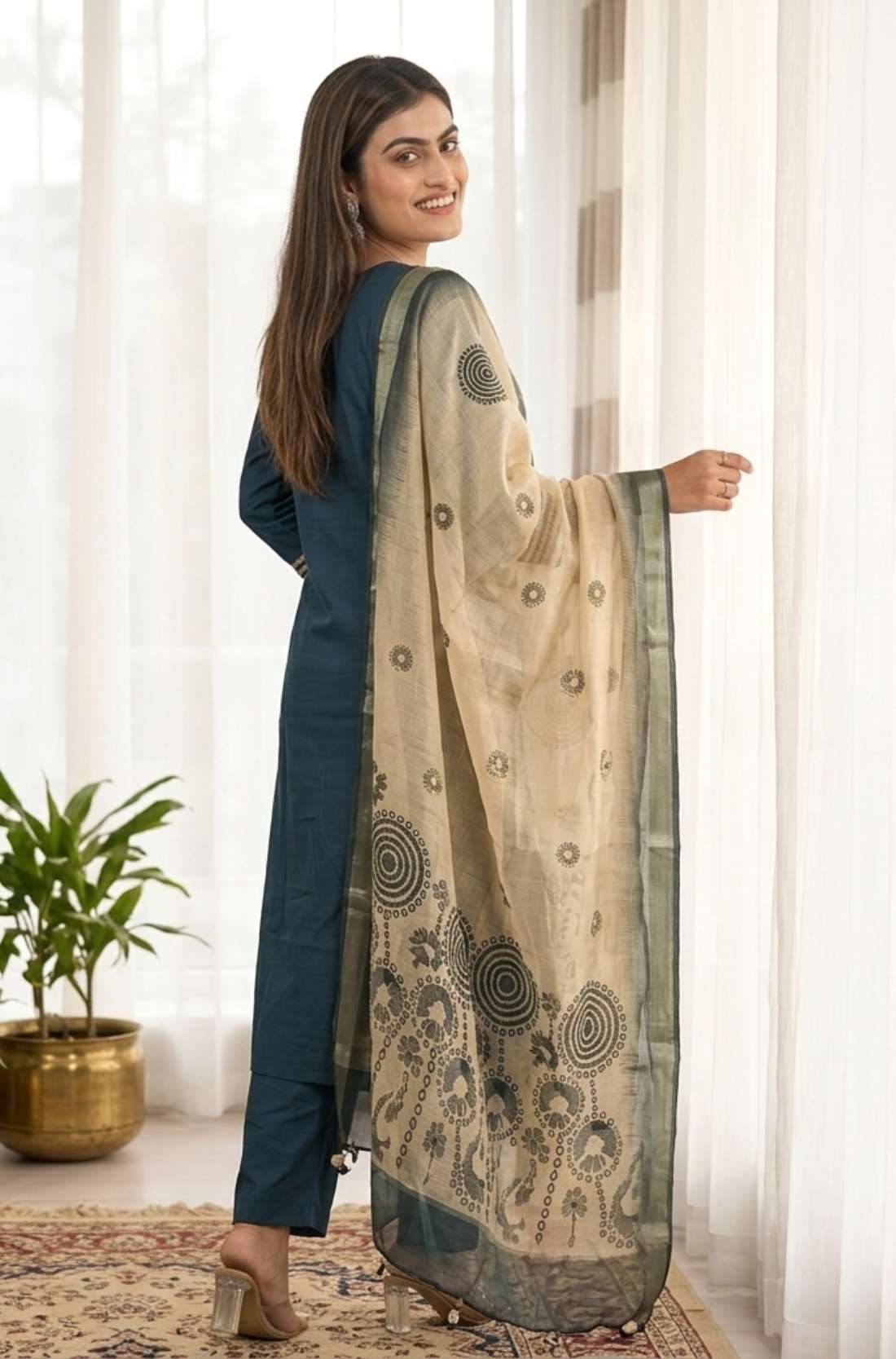 Side profile view of a model in a dark blue silk ethnic suit set with matching pants and a draped orange chanderi dupatta