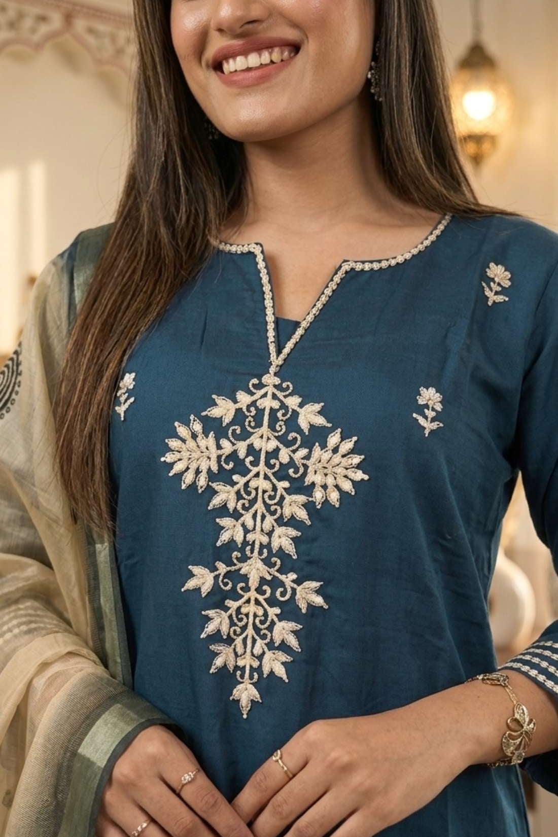 Close up shot of the intricate floral aari embroidery and button neckline details on a dark blue silk kurta