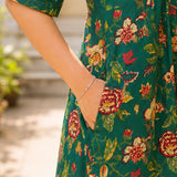 Close-up detail shot showcasing a convenient functional side utility pocket seamlessly integrated into the seam of a dark green floral printed cotton frock-style kurti.