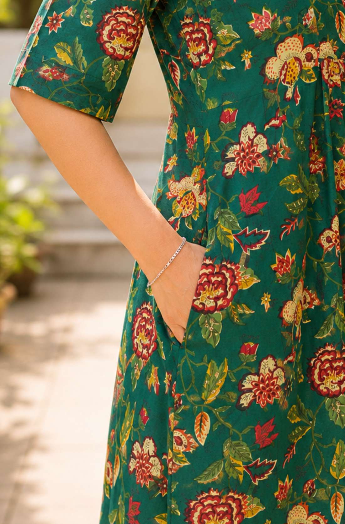 Close-up detail shot showcasing a convenient functional side utility pocket seamlessly integrated into the seam of a dark green floral printed cotton frock-style kurti.