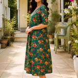 Side profile view of a woman posing in a flared dark green cotton floral print frock-style kurti, highlighting the comfortable elbow-length sleeves and elegant drape.