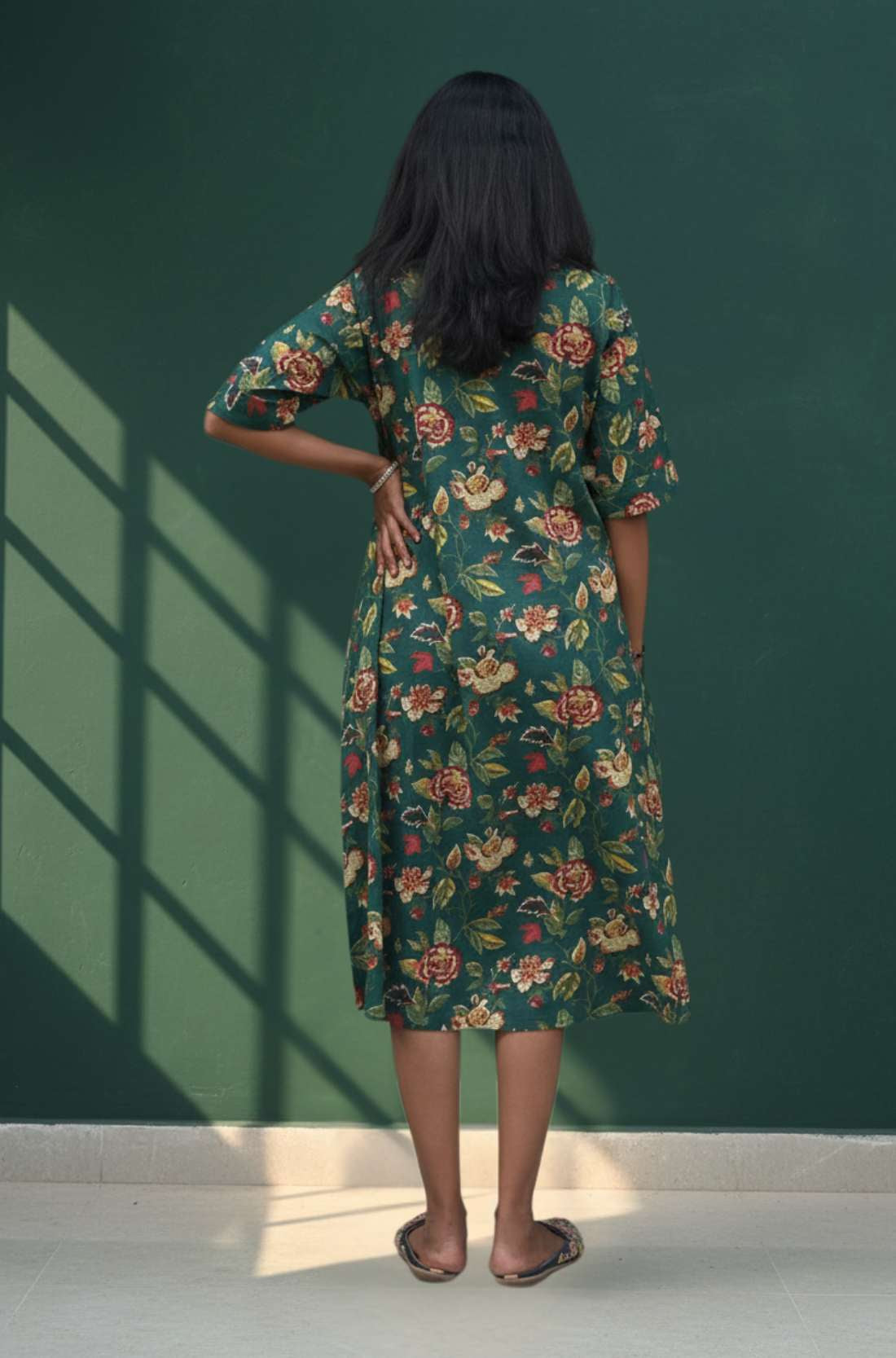 Back view of dark green floral cotton midi dress with short sleeves and relaxed fit.
