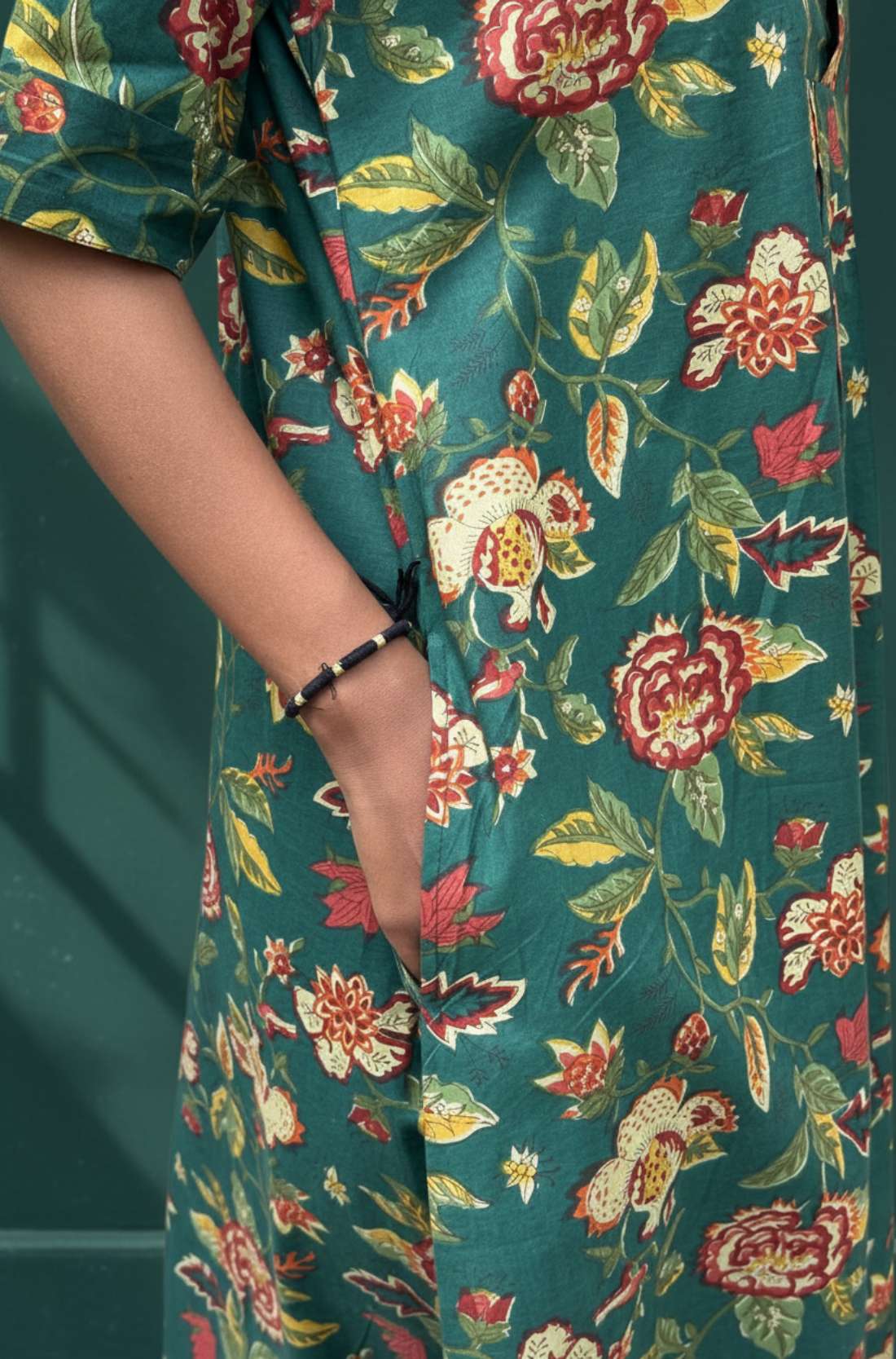 Close-up of side pocket on dark green floral cotton midi dress.