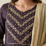 Close up shot of the intricate silver chain stitch hand embroidery patterns on the yoke and round neckline of a dark purple crepe kurta