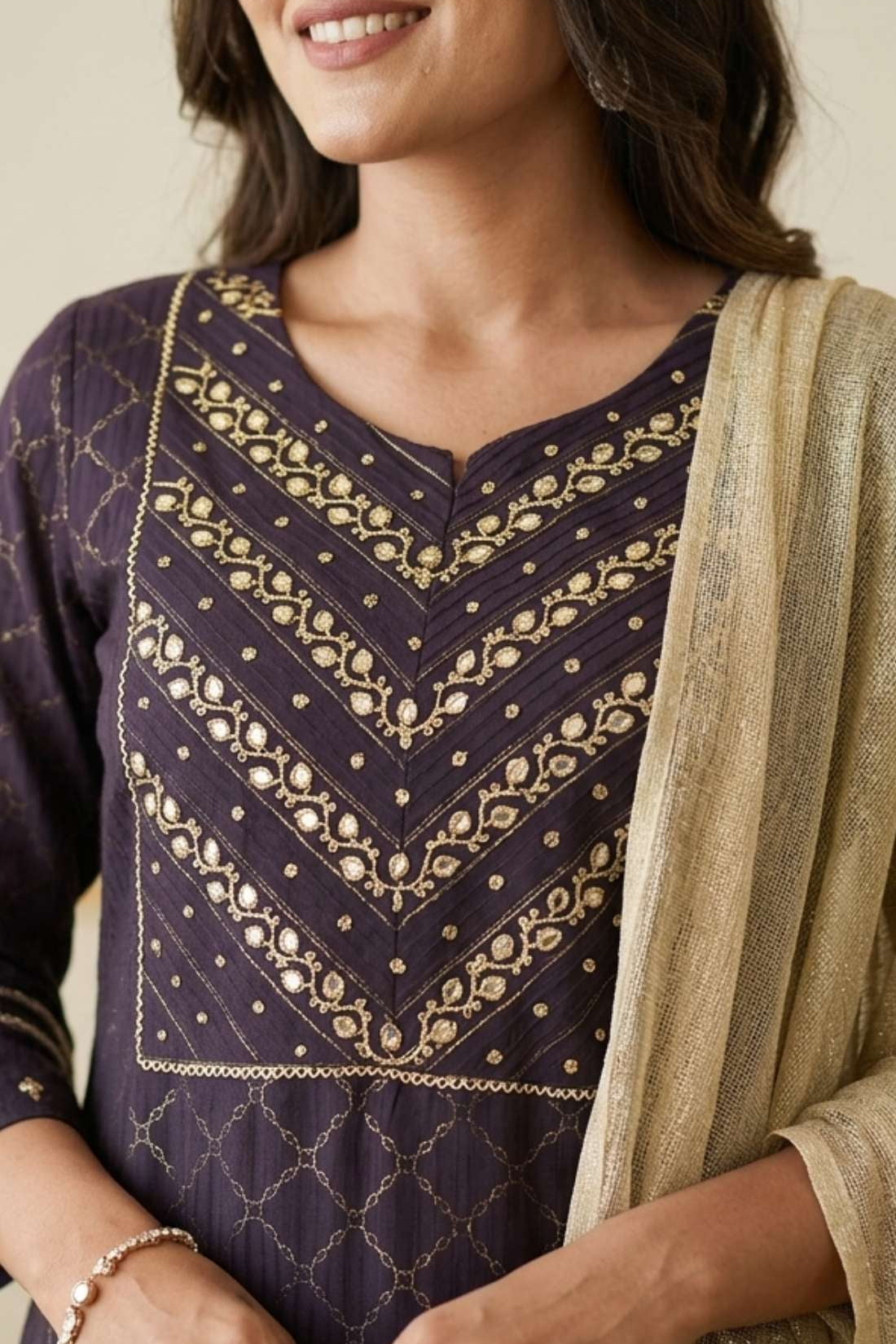 Close up shot of the intricate silver chain stitch hand embroidery patterns on the yoke and round neckline of a dark purple crepe kurta