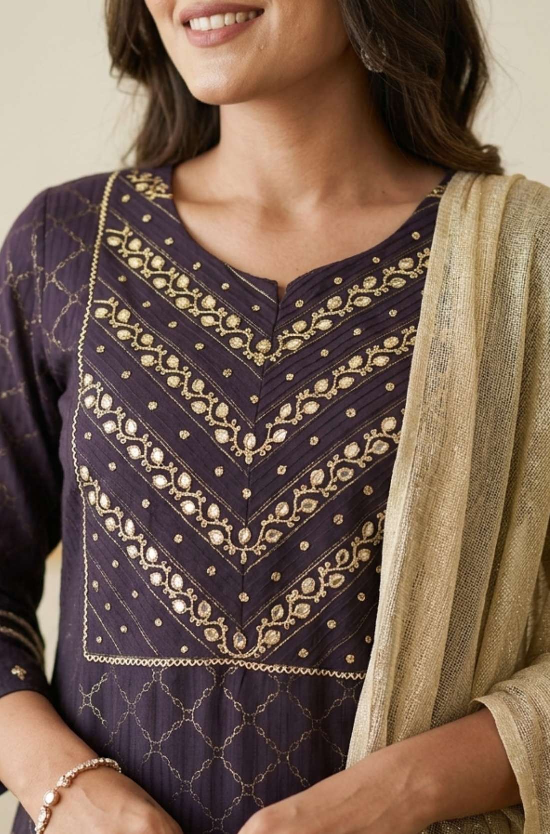 Close up shot of the intricate silver chain stitch hand embroidery patterns on the yoke and round neckline of a dark purple crepe kurta