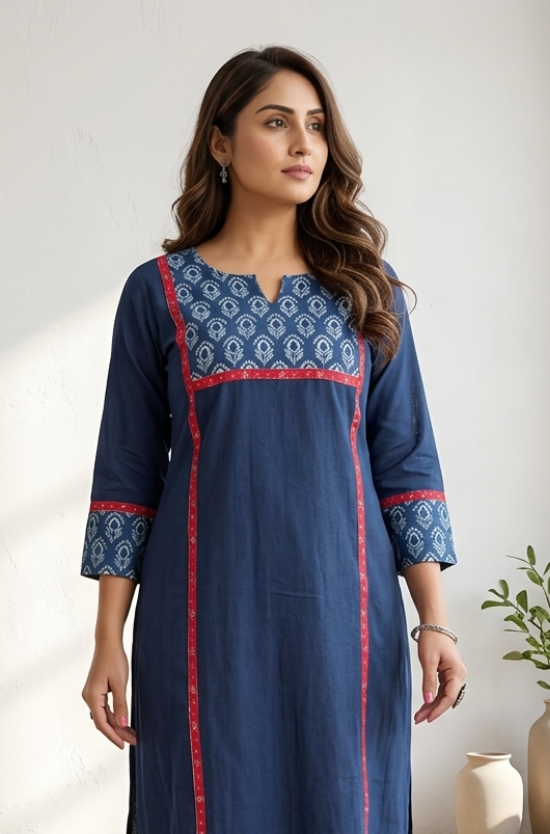 Woman standing indoors wearing an elegant blue office wear kurti featuring a printed neckline and red accents.