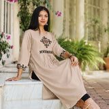 Model sitting in embroidered beige A-line rayon kurta with cross stitch yoke and sleeve detail
