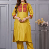 Front full length view of a model wearing an embroidered ochre yellow yoke cotton straight kurta set with pocketed pants and a printed dupatta