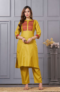 Front full length view of a model wearing an embroidered ochre yellow yoke cotton straight kurta set with pocketed pants and a printed dupatta