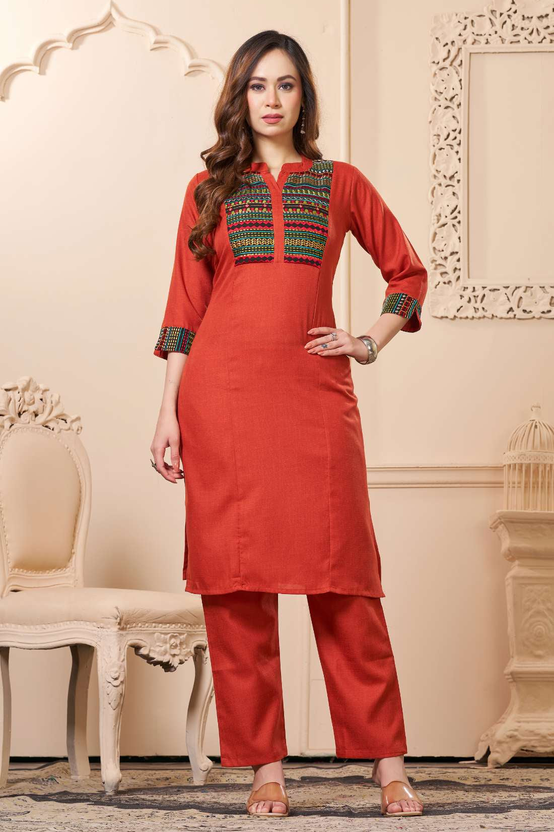 Front full length view of a model wearing an embroidered rust orange yoke cotton straight kurta set with pocketed pants and a printed dupatta