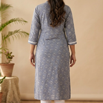 A rear view of a woman wearing a grey-blue printed straight kurta and white pants, highlighting the garment fit.