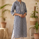 A full-length studio shot of a woman modeling a grey-blue printed straight kurta with white pants.