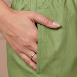 Close up view showcasing a functional side utility pocket tailored into a light green pure cotton kurta with vibrant floral cross stitch embroidery details, with a hand resting inside the pocket over straight pants.