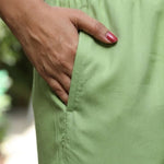 Close up view highlighting the convenient functional side utility pocket tailored into the matching straight trousers of a light green embroidered cotton kurta set, showing a hand resting inside the pocket.