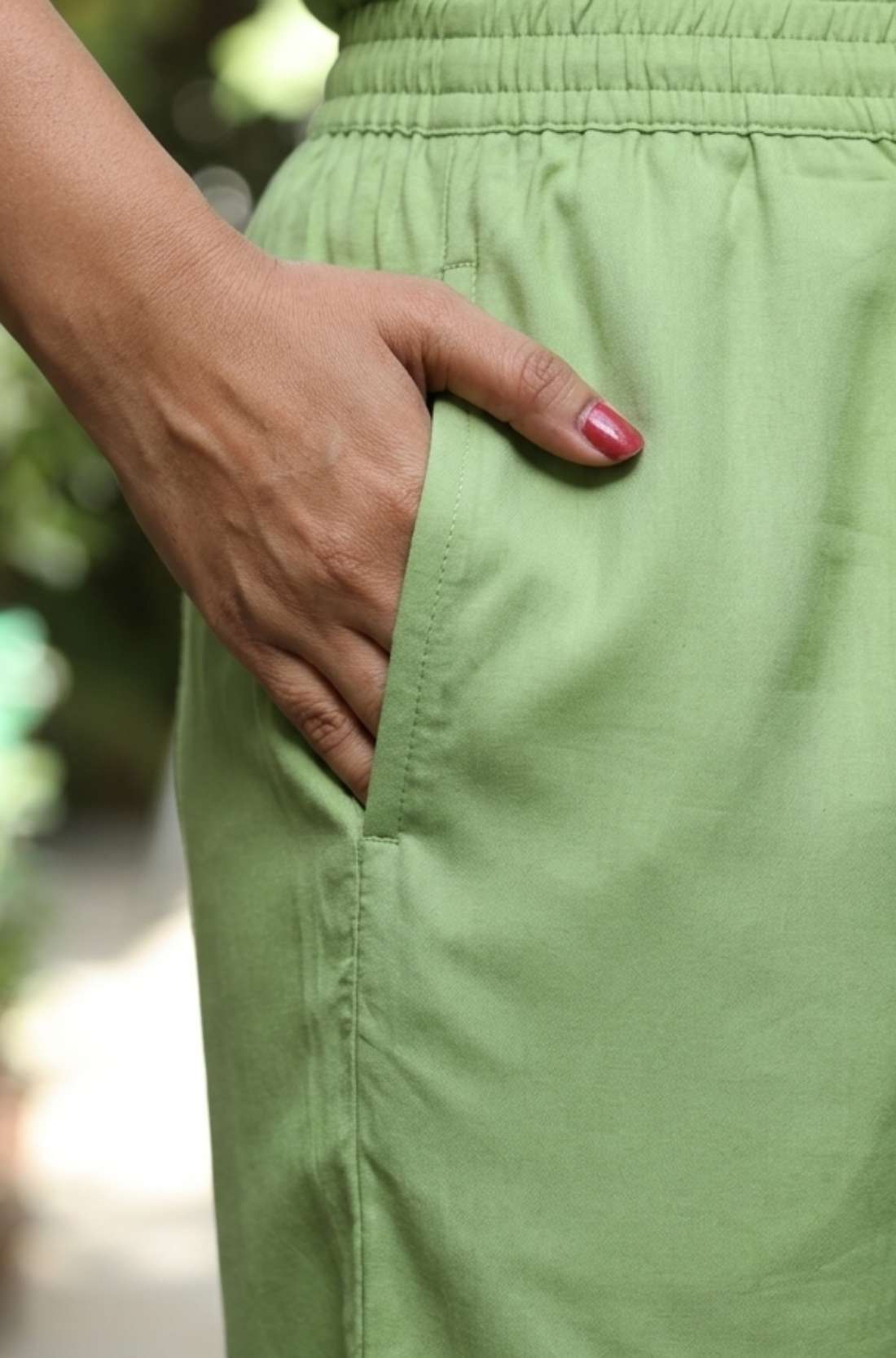 Close up view highlighting the convenient functional side utility pocket tailored into the matching straight trousers of a light green embroidered cotton kurta set, showing a hand resting inside the pocket.