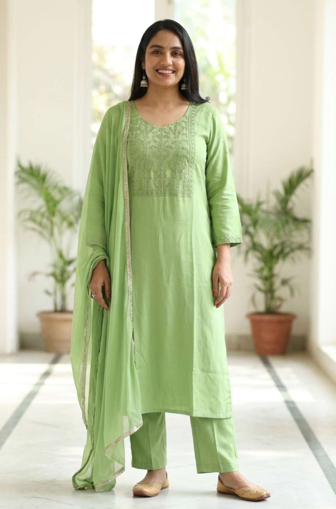 Front full length view of a woman wearing a light green embroidered kurta set with straight pants and a matching printed dupatta