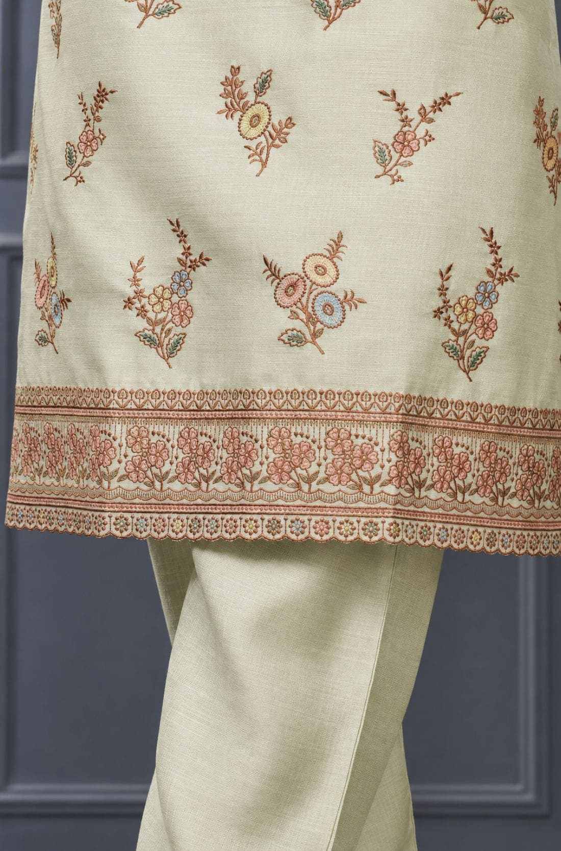 Close-up of floral embroidery and decorative scalloped border on a light green silk blend kurta for women.